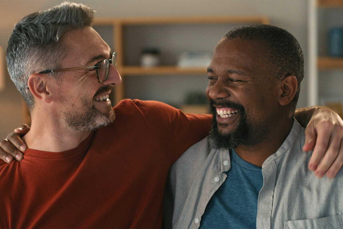 A living room scene with two men, a gay couple, wearing smiles of pure happiness.