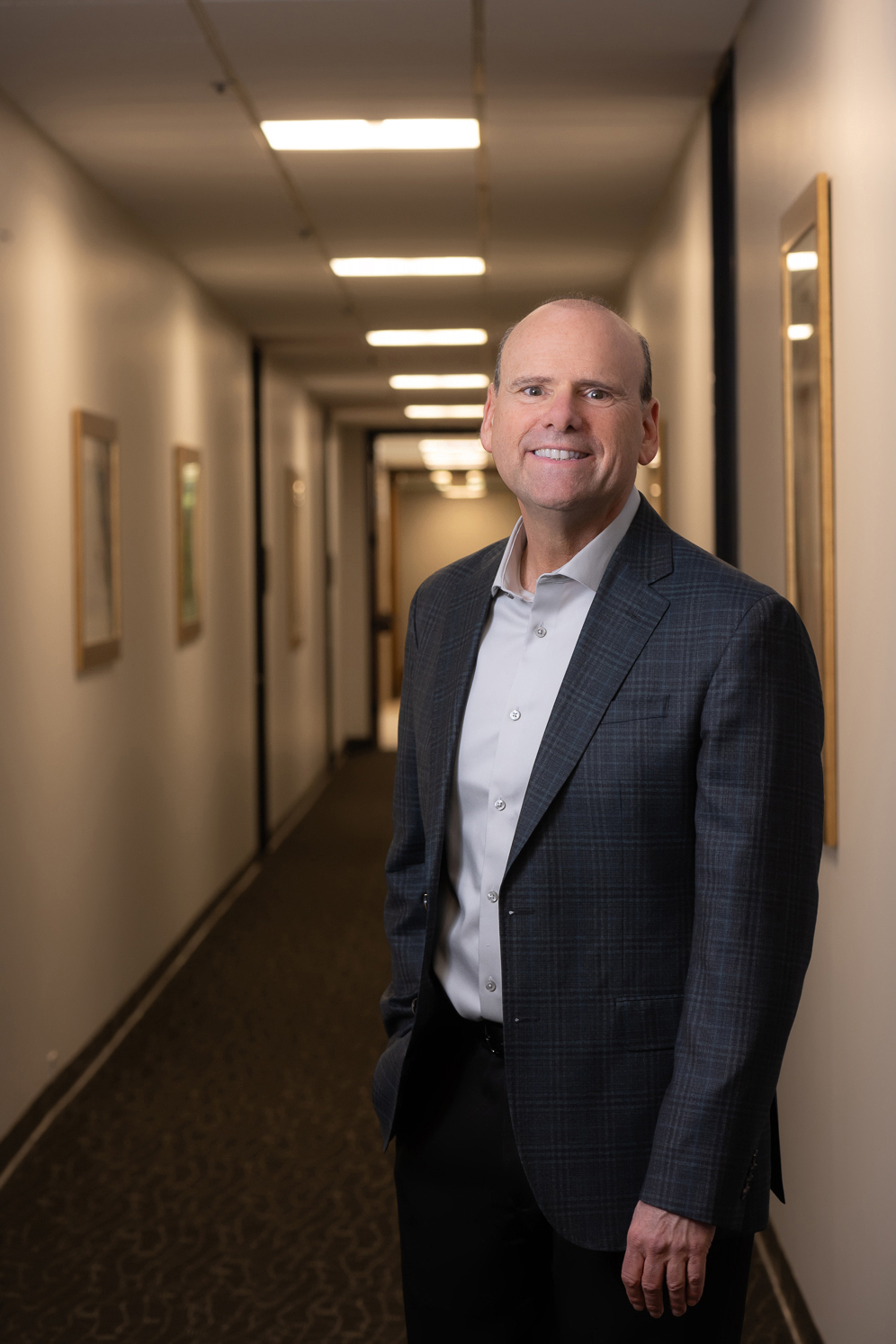Michael dressed in a suit is positioned in a hallway, exuding professionalism.