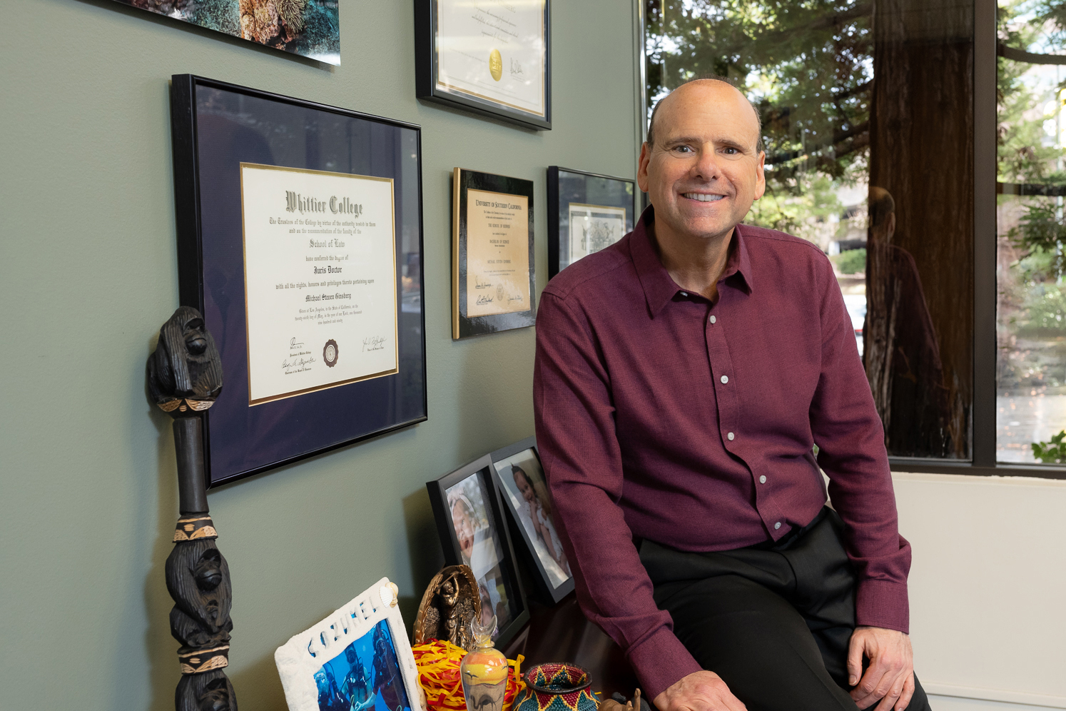 user-inserted A man dressed in a purple shirt is sitting on a chair, exuding a calm demeanor while observing his surroundings.