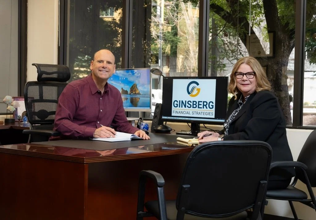 user-inserted Two colleagues seated at a desk in an office, discussing work-related matters.