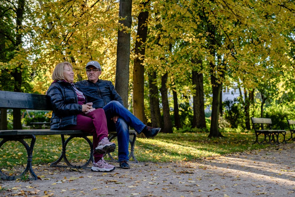 user-inserted Middle-aged couple sitting on a park bench discussing their future plans - Social Security claiming age